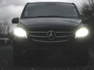 Dunkler Mercedes-Van bei Dämmerung mit eingeschaltetem Licht