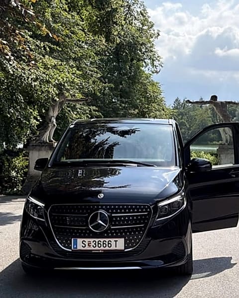 Die schwarze Mercedes V-Klasse von Salzburg Chauffeur mit geöffneter Fondtür, aufgenommen in einer Salzburger Parkanlage